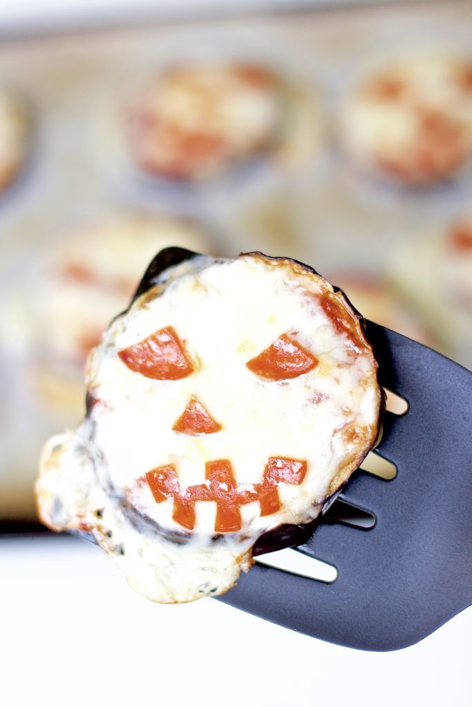 Satisfy all of the ghouls in your life this Halloween when you make these spooky Eggplant Jack-O-Lantern Pizzas for your fright fest. Simple to assemble, and ready in less than 30 minutes, they are perfect for getting the little ones involved as well. Keto Pizza | Ketogenic Diet | Keto Recipes | Halloween Recipe | Kid Friendly | Spooky | Pumpkins | Low Carb | Low Calorie | Gluten-Free Pizza | Scary | Healthy | Fall Recipe | Weight Loss | Easy |