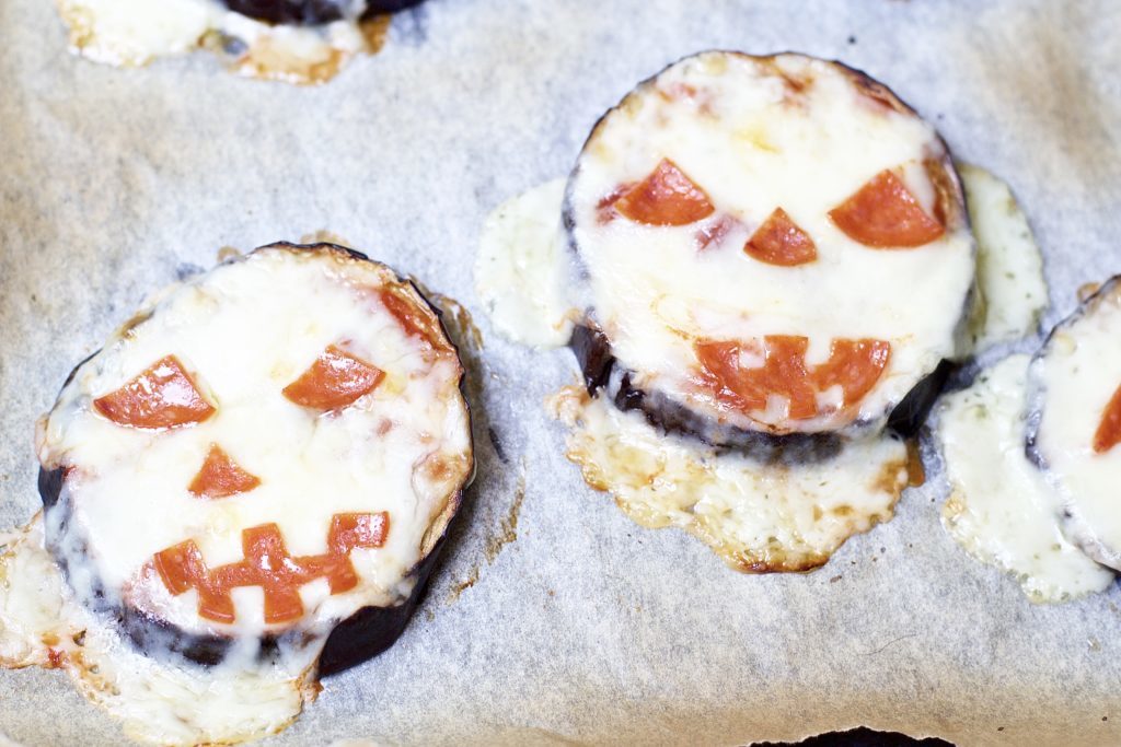 Satisfy all of the ghouls in your life this Halloween when you make these spooky Eggplant Jack-O-Lantern Pizzas for your fright fest. Simple to assemble, and ready in less than 30 minutes, they are perfect for getting the little ones involved as well. Keto Pizza | Ketogenic Diet | Keto Recipes | Halloween Recipe | Kid Friendly | Spooky | Pumpkins | Low Carb | Low Calorie | Gluten-Free Pizza | Scary | Healthy | Fall Recipe | Weight Loss | Easy |