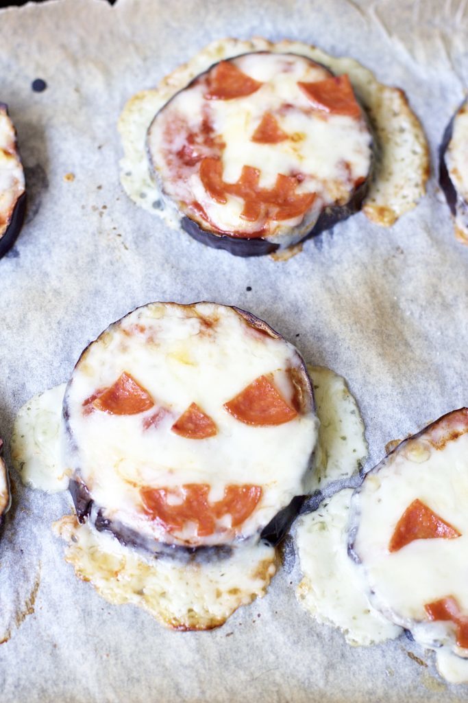 Satisfy all of the ghouls in your life this Halloween when you make these spooky Eggplant Jack-O-Lantern Pizzas for your fright fest. Simple to assemble, and ready in less than 30 minutes, they are perfect for getting the little ones involved as well. Keto Pizza | Ketogenic Diet | Keto Recipes | Halloween Recipe | Kid Friendly | Spooky | Pumpkins | Low Carb | Low Calorie | Gluten-Free Pizza | Scary | Healthy | Fall Recipe | Weight Loss | Easy |