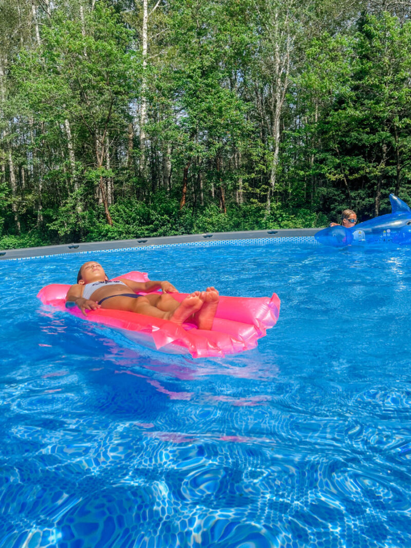 Child relaxing floating in a lounge floatie pool float of an Intex Ultra XTR above ground pool